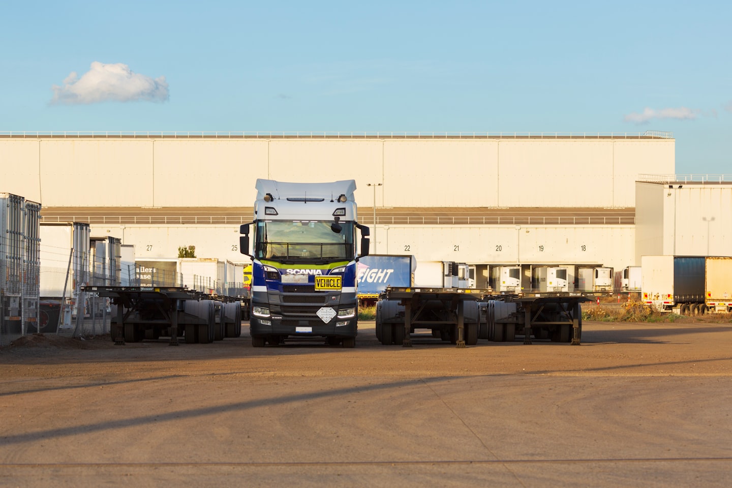 Blå och vit Scania-semitrailer parkerad på en logistikgård.