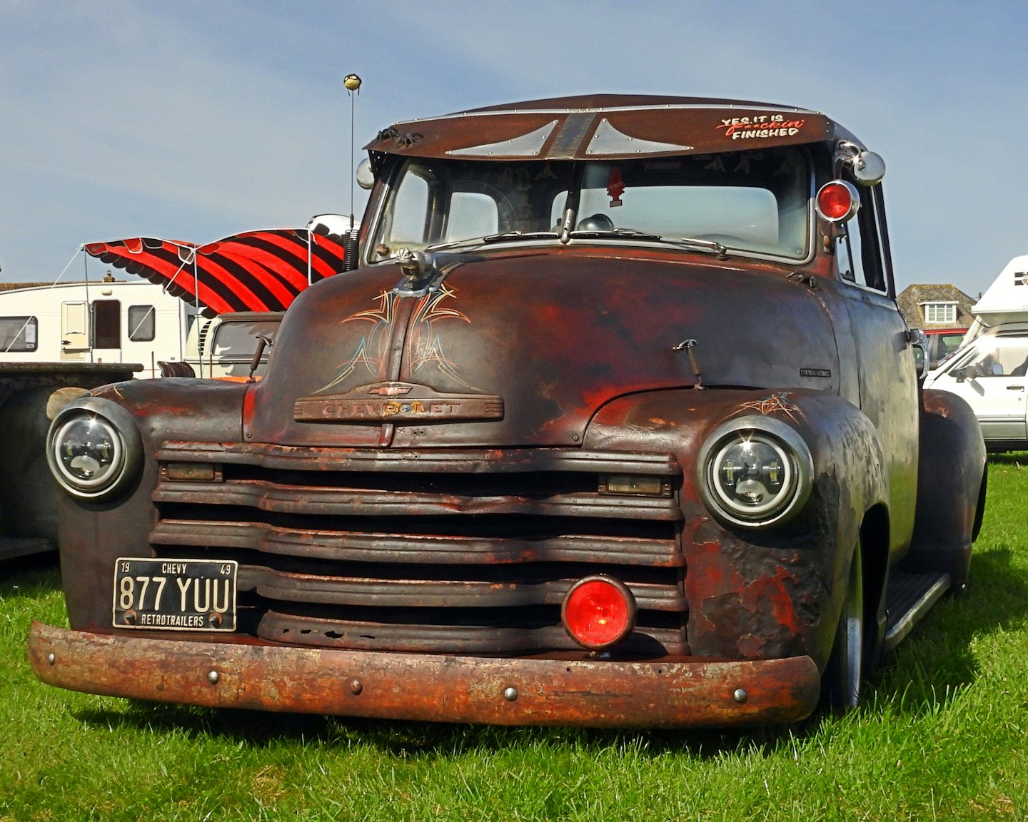 Gammal rostig pickup parkerad på grönt gräs.