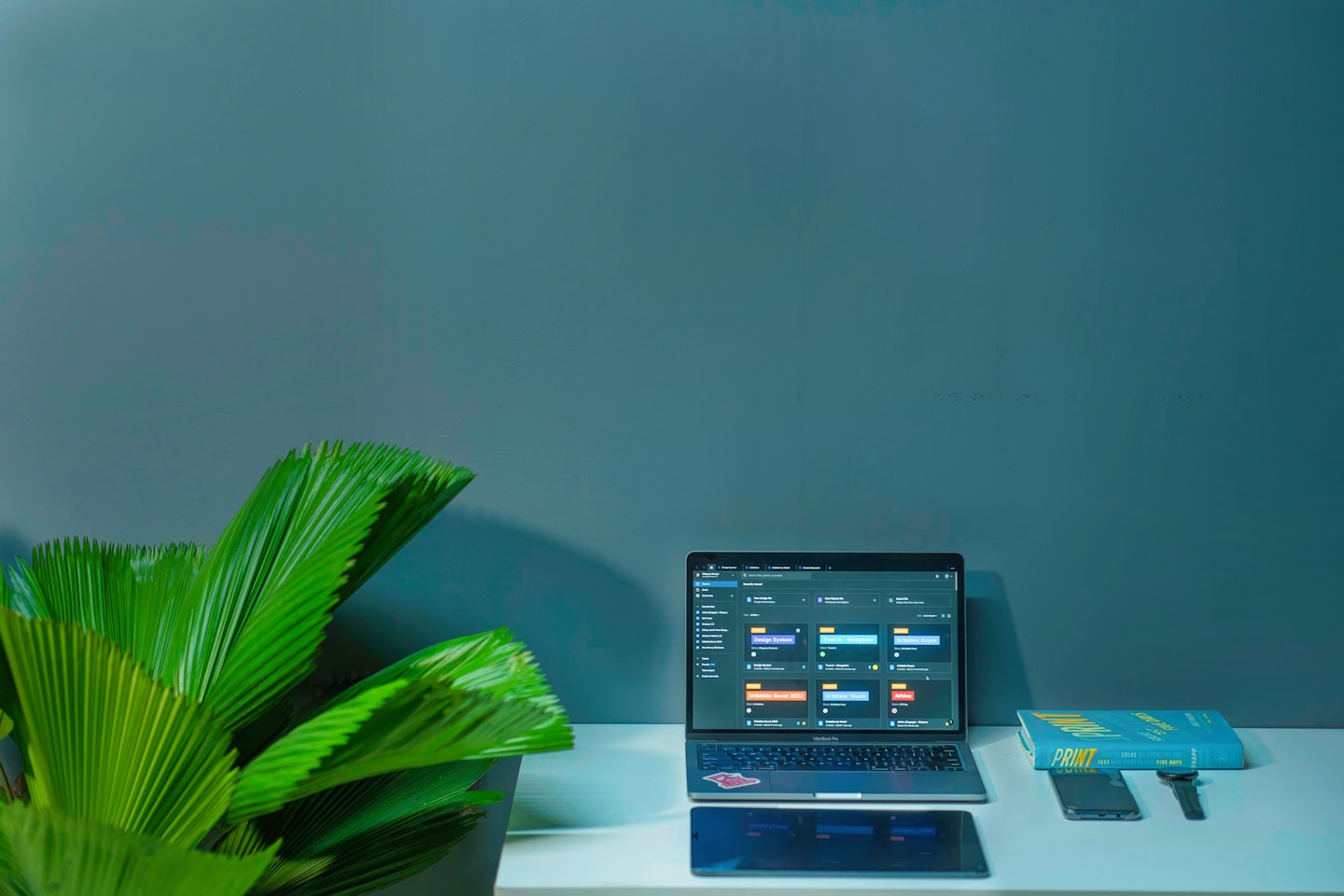 Dator med projektledningsprogramvara på ett rent skrivbord med en växt.